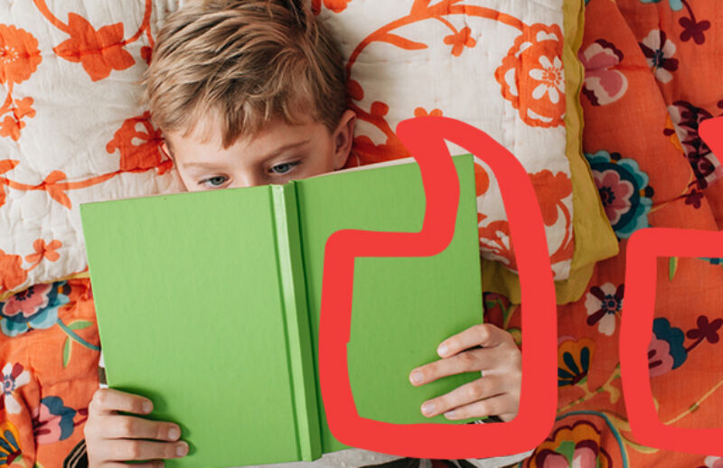 A boy laying down reading a book