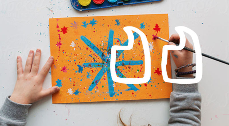 A kid painting water colour on an orange paper